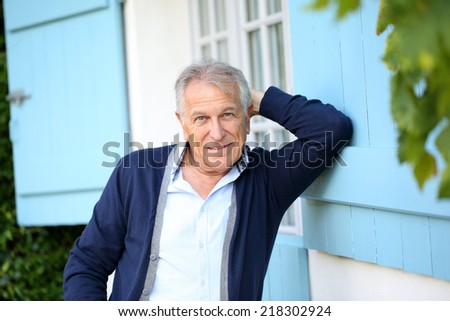 Senior man leaning on wall outside the house