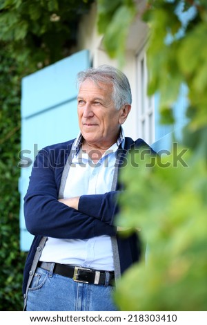 Senior man leaning on wall outside the house