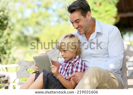 Daddy and son playing with tablet outside