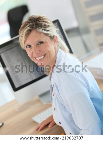 Portrait of cheerful blond woman in office