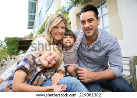 Family of four sitting in front of house