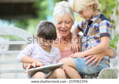 Grandmother with kids playing games on tablet