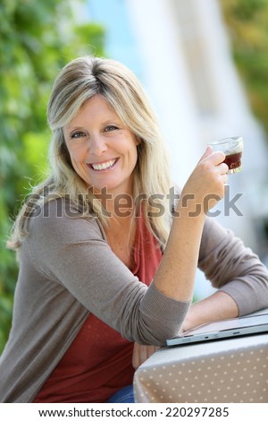 Mature woman relaxing with tablet and coffee in garden