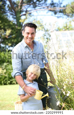 Father and son watering plants in garden