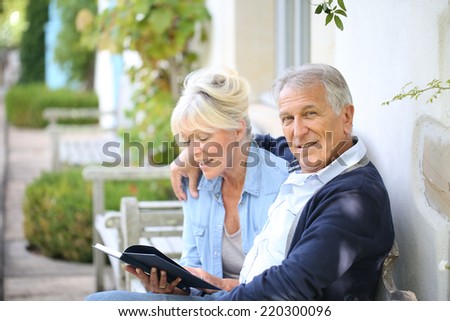 Senior couple reading book outside their house