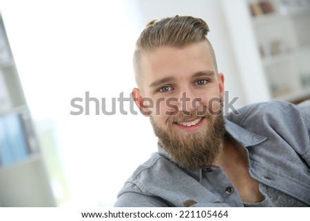 Portrait of trendy guy with beard relaxing at home