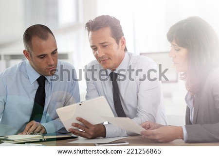 Business people meeting around desk with tablet