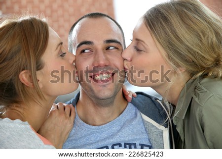 Lucky guy being kissed by 2 girl friends