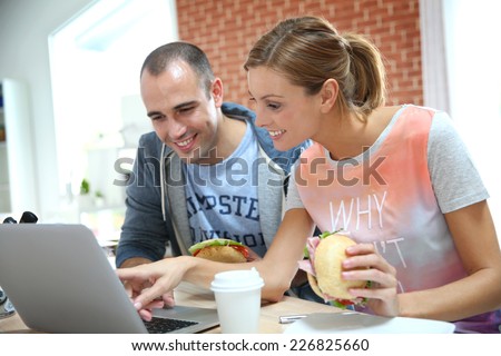 Roommates eating sandwich in front of laptop