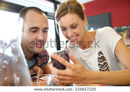 Young people in snack bar, connected on smartphone