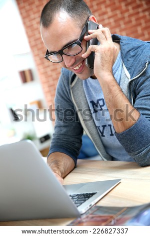 Guy with eyeglasses using smartphone at home
