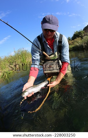 Fly fisherman holding recently caught fish