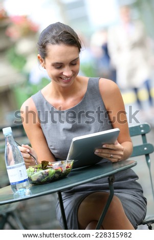Businesswoman working with tablet while having lunch