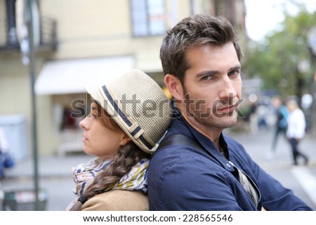Couple in street leaning back to back