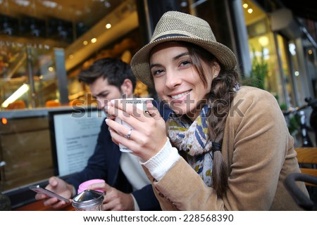 Woman with hat sitting at coffee shop holding hot drink cup