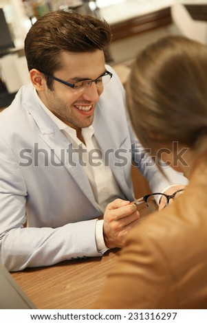Optician with client trying eyeglasses in optical center
