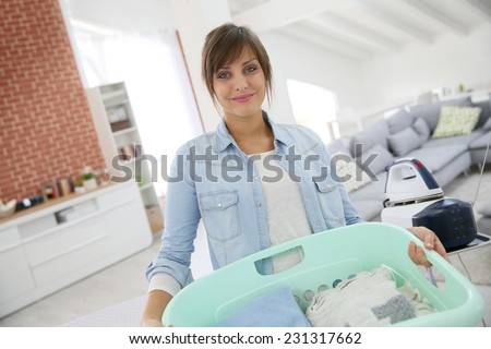 Young home service woman holding basket of folded laundry