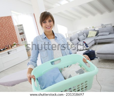 Young home service woman holding basket of folded laundry