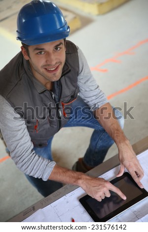 Builder with blue security helmet using tablet