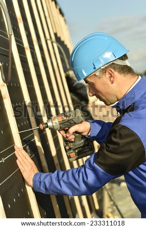 Construction worker using electric drill on building site