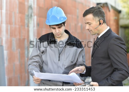 Contractor on building site checking different points with worker