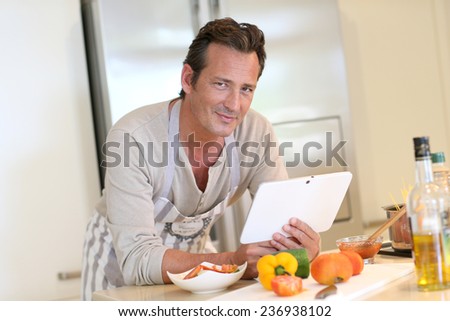 Handsome man in kitchen looking at digital tablet for recipe