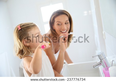 Mother and daughter in bathroom brushing her teeth