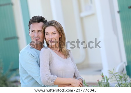 Middle-aged couple embracing in front of house