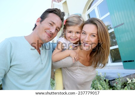 Portrait of happy family standing in front of house