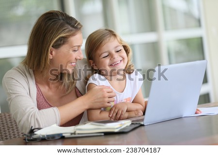 Little girl looking at laptop computer with her mom