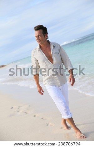 Handsome 40-year-old man walking on beach