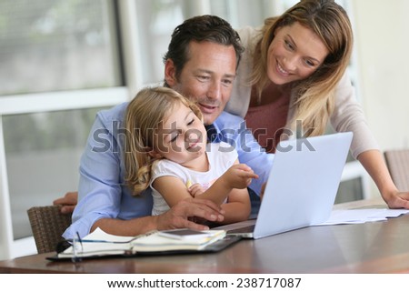 Parents with little girl looking at pictures on computer