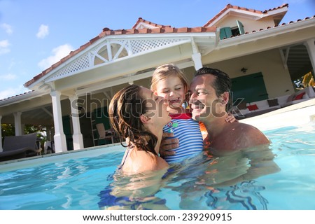 Family playing in swimming pool of private villa