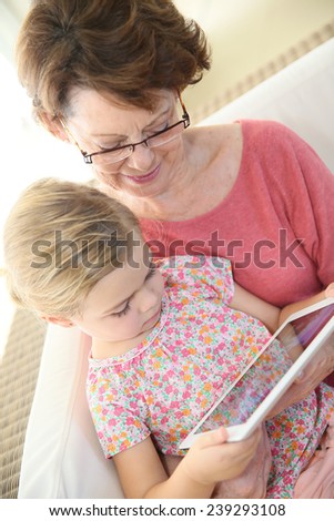 4-year-old girl with grandma playing on digital tablet