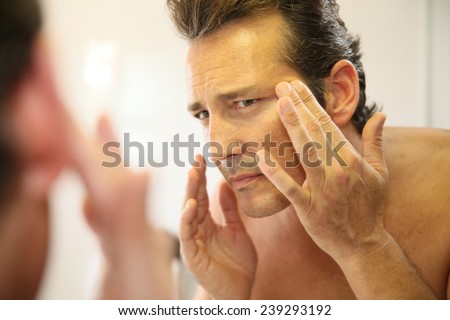 Middle-aged man in bathroom applying facial lotion