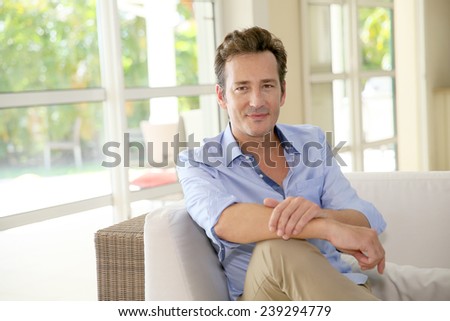 Portrait of single middle-aged man sitting in sofa