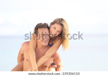 Cheerful 40-year-old man giving piggyback ride to woman