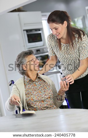 Portrait of elderly woman in wheelchair with home carer
