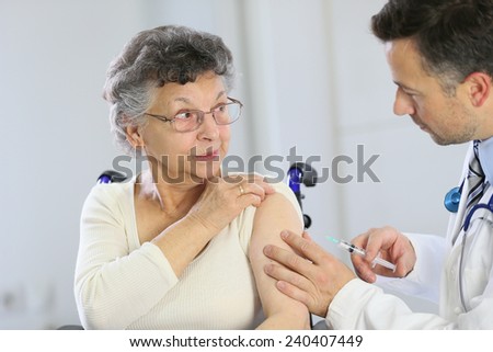 Doctor doing vaccine injection to elderly woman