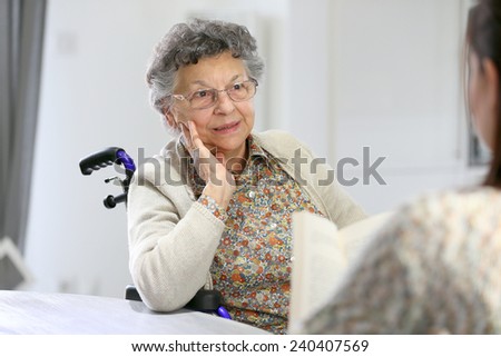 Homec arer reading book to old woman in nursing home