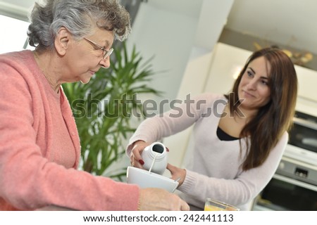Home helper serving breakfast to elderly woman