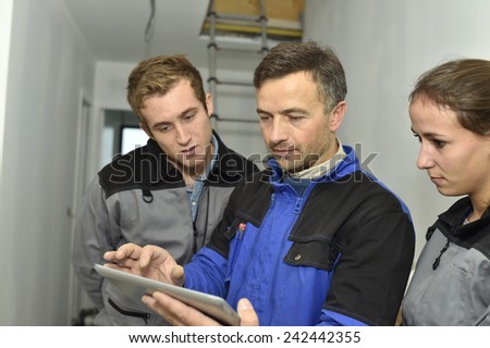 Electrician explaining trainees building electric plan