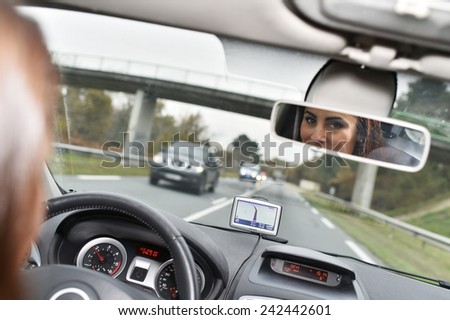 Woman in car binnacle looking at rear view mirror