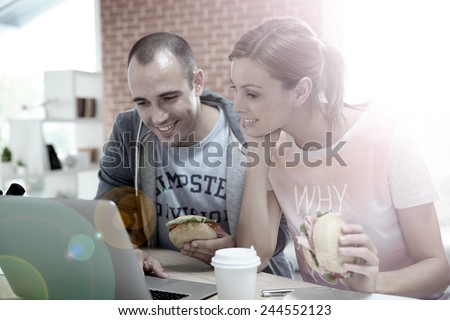 Roommates eating sandwich in front of laptop