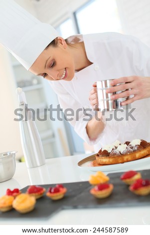 Pastry cook spreading icing sugar on tart