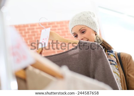 Beautiful woman in store choosing clothes on sale