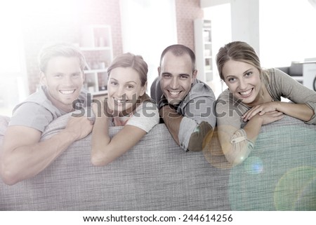 Cheerful roommates sitting in sofa at home