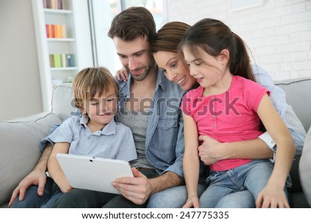 Family of four playing with digital tablet at home