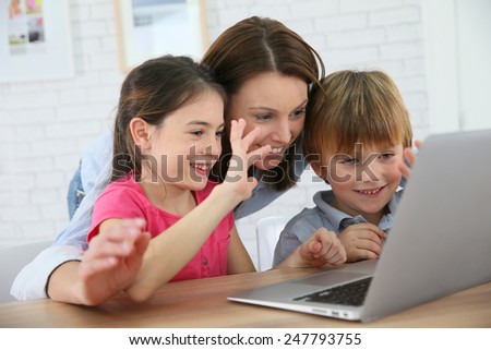 Family of three using laptop video call camera