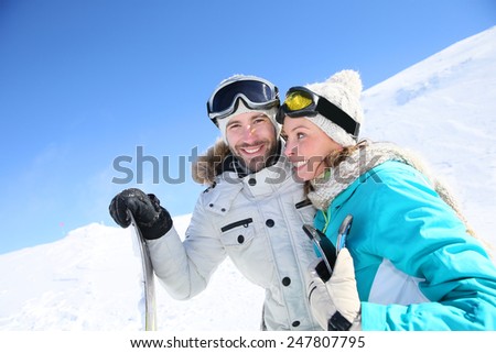 Cheerful couple of skiers ready to go down ski slope